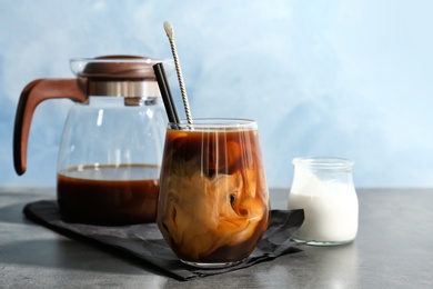 Glass with cold brew coffee and milk on table