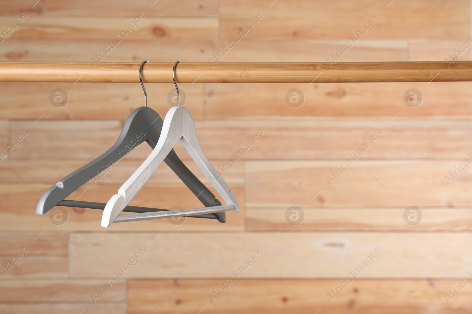 Photo of Rack with clothes hangers on wooden background, space for text