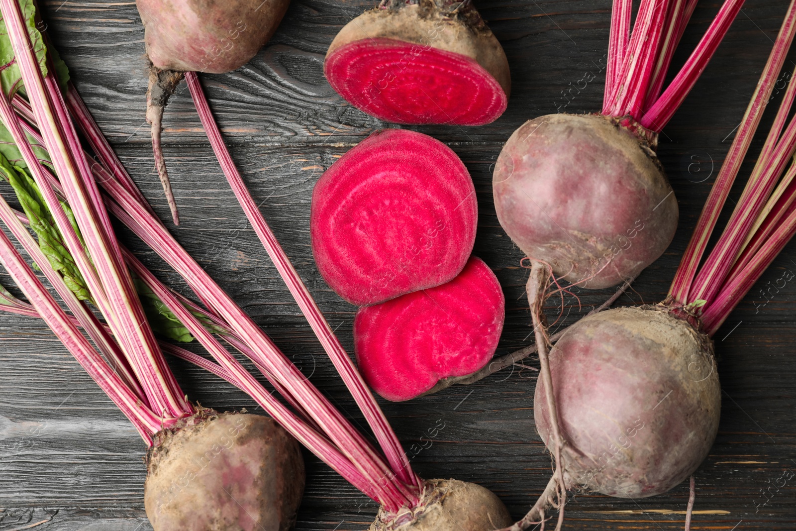 Photo of Cut and whole raw beets on wooden table