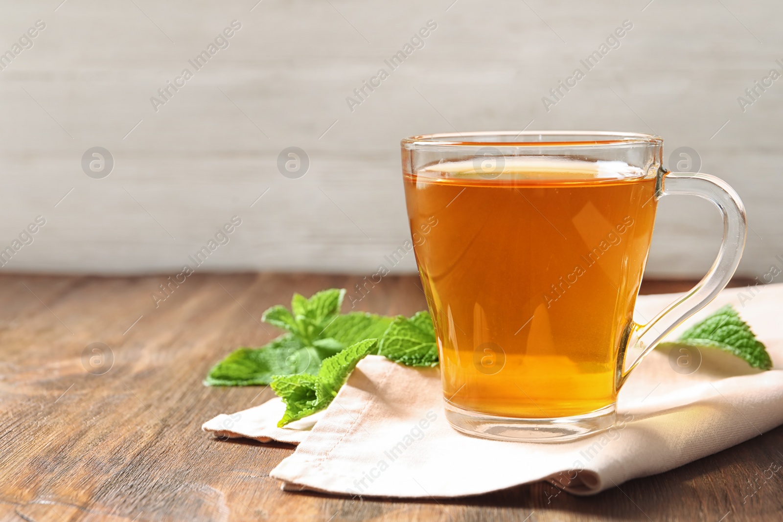 Photo of Cup with hot aromatic mint tea on wooden table