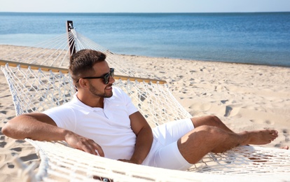 Photo of Young man relaxing in hammock on beach