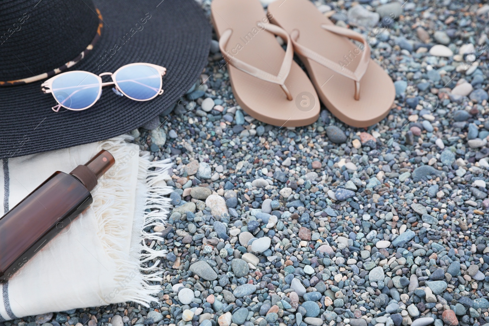 Photo of Set of different stylish beach accessories on pebble seashore. Space for text