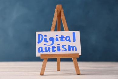Photo of Mini easel with phrase Digital Autism on white wooden table