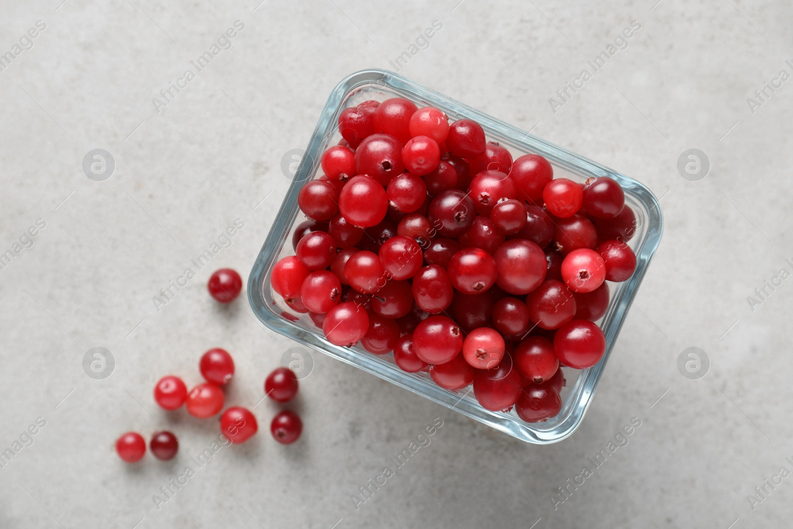 Photo of Cranberries in bowl on light grey table, top view