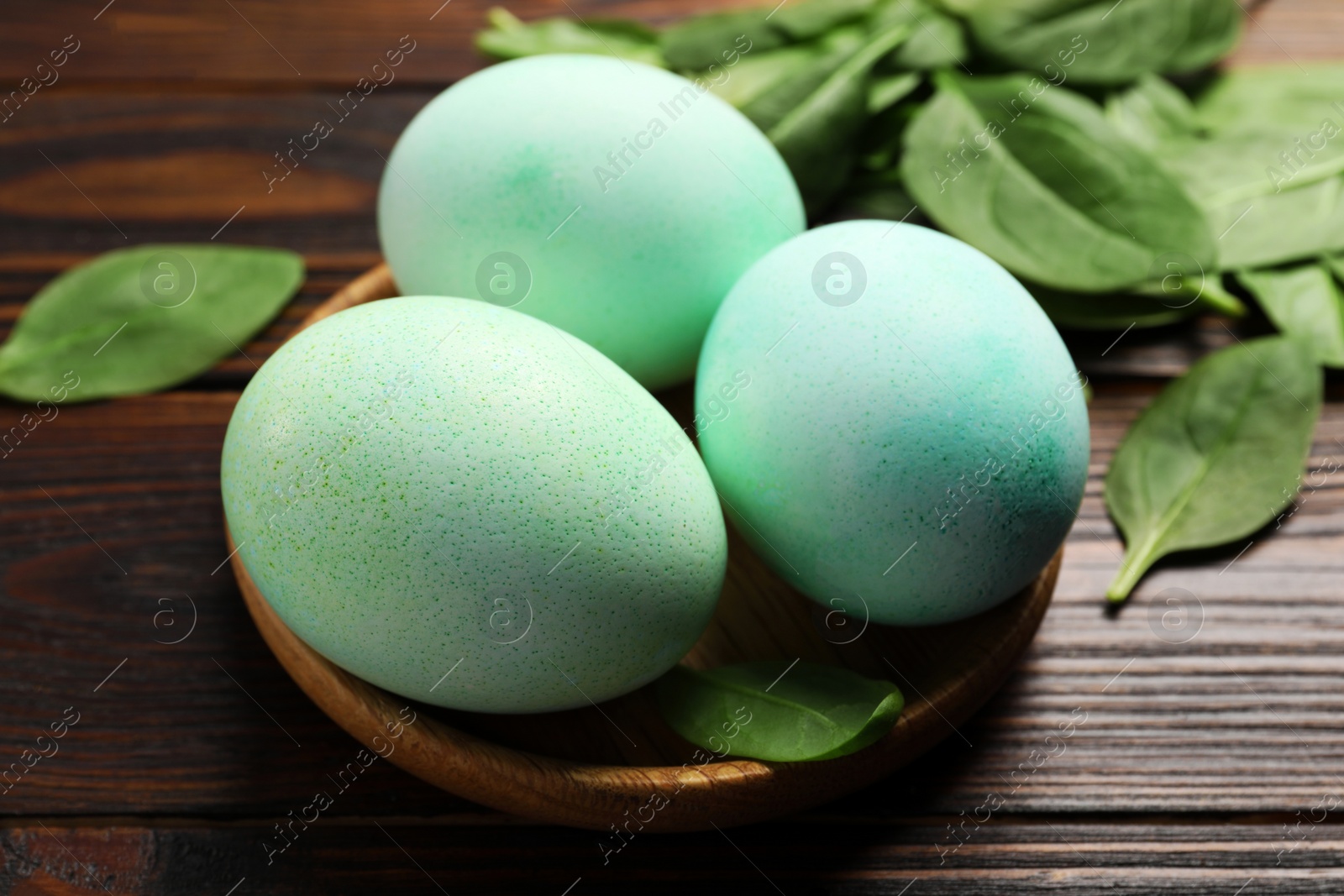 Photo of Naturally painted Easter eggs on wooden table, closeup. Spinach used for coloring