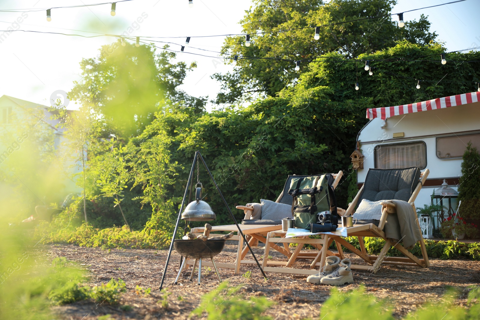 Photo of Deck chairs and travel accessories near modern motorhome. Camping season