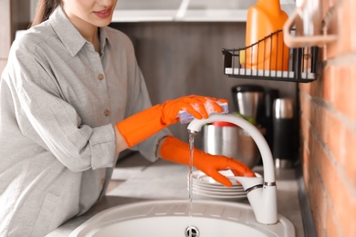 Young woman cleaning tap in kitchen