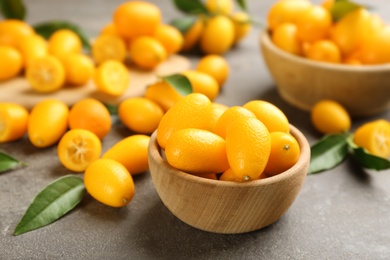 Fresh ripe kumquats in bowl on grey table