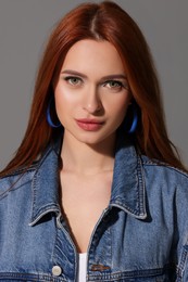 Beautiful young woman in denim jacket on gray background