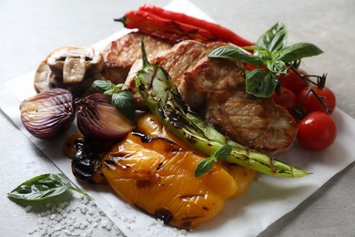 Tasty grilled meat and vegetables on light table, closeup