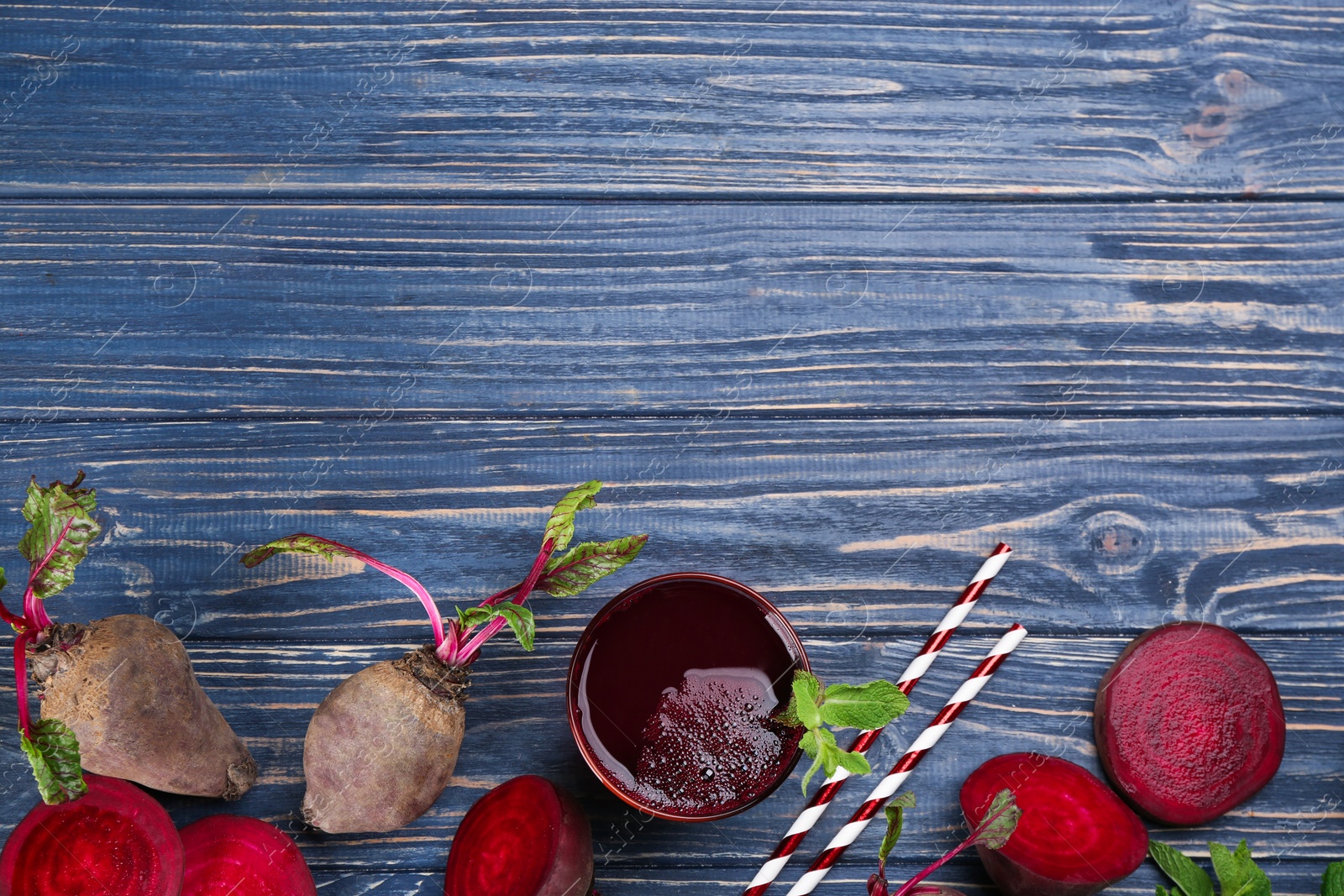 Photo of Freshly made beet juice on blue wooden table, flat lay. Space for text