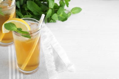Photo of Delicious iced tea with lemon and mint on white wooden table. Space for text