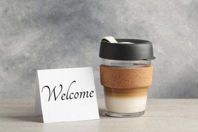 Image of Paper note with word Welcome and cup of coffee on table