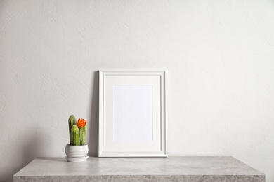 Mockup of blank frame and cactus on table