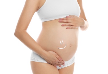 Smile painted with body cream on pregnant woman's belly against white background, closeup