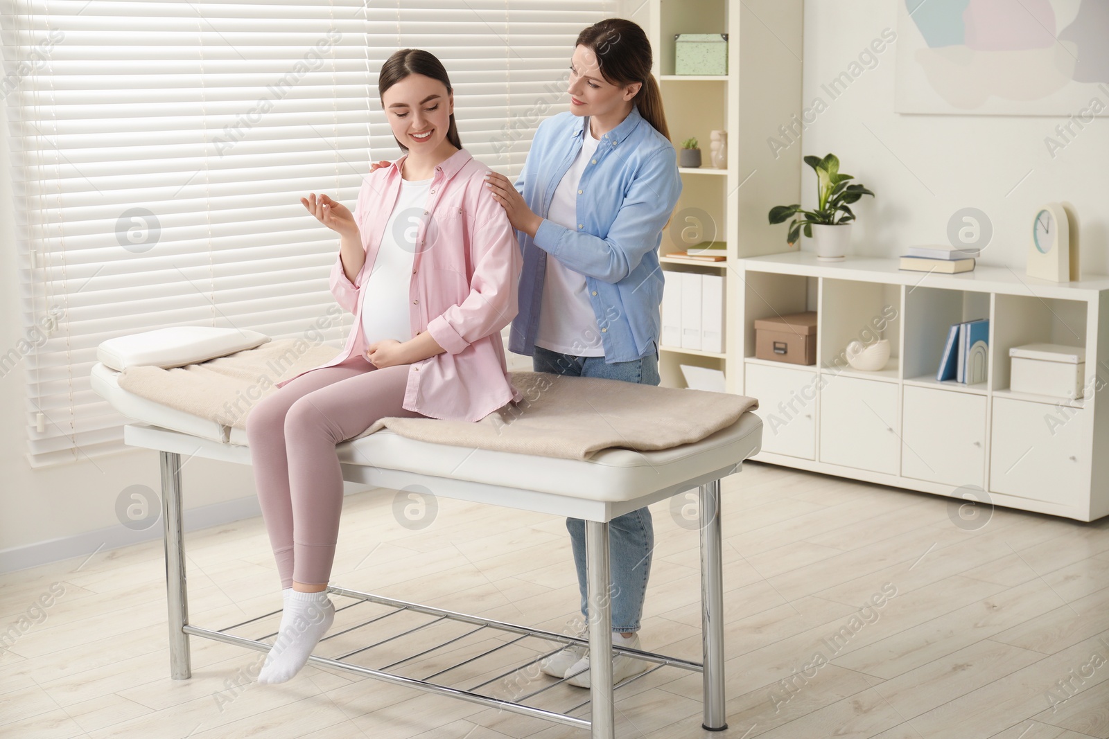 Photo of Doula taking care of pregnant woman indoors. Preparation for child birth