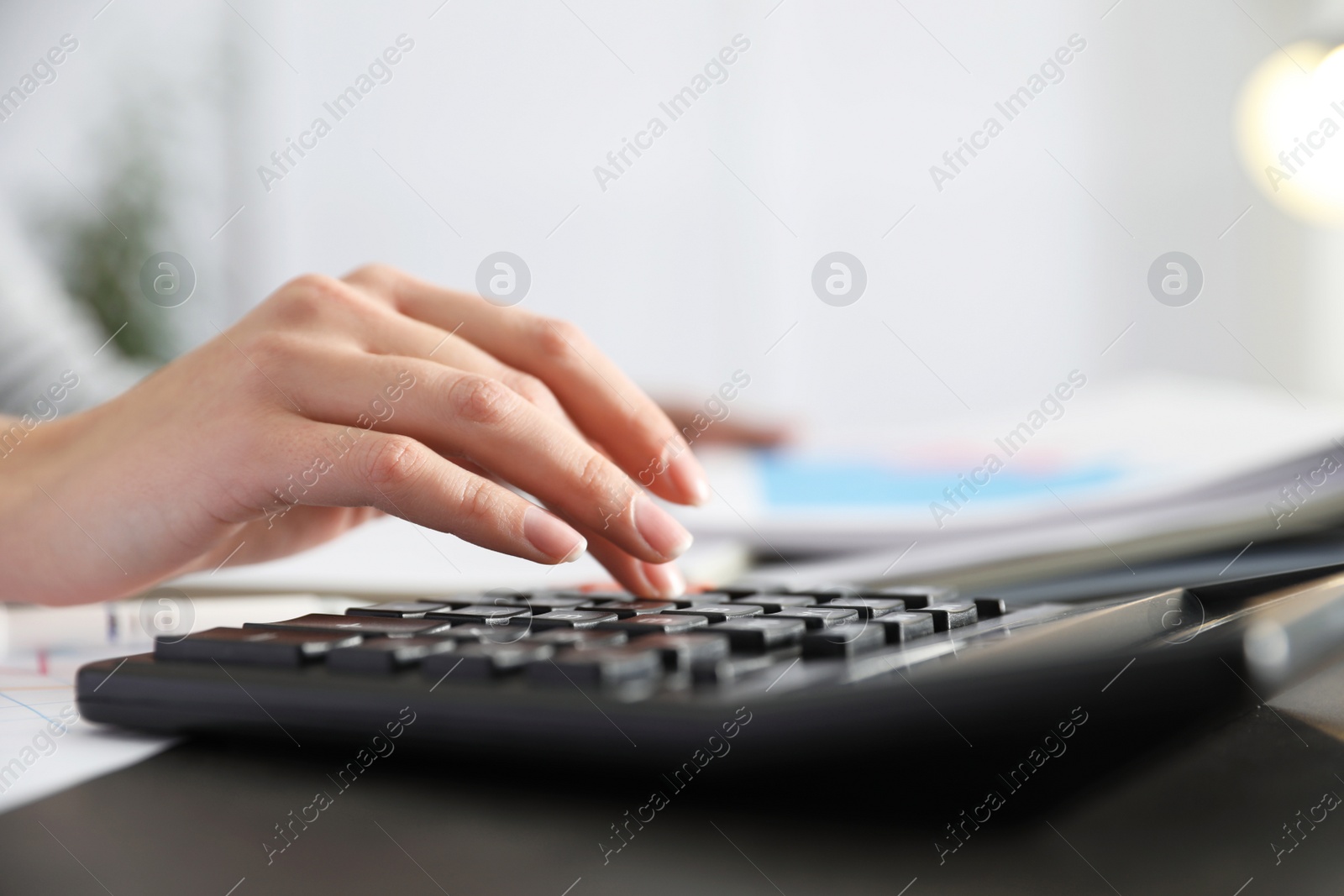 Photo of Office employee working with calculator and documents at table, closeup