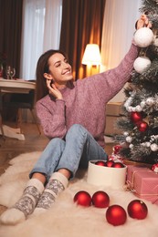 Photo of Young woman decorating Christmas tree at home