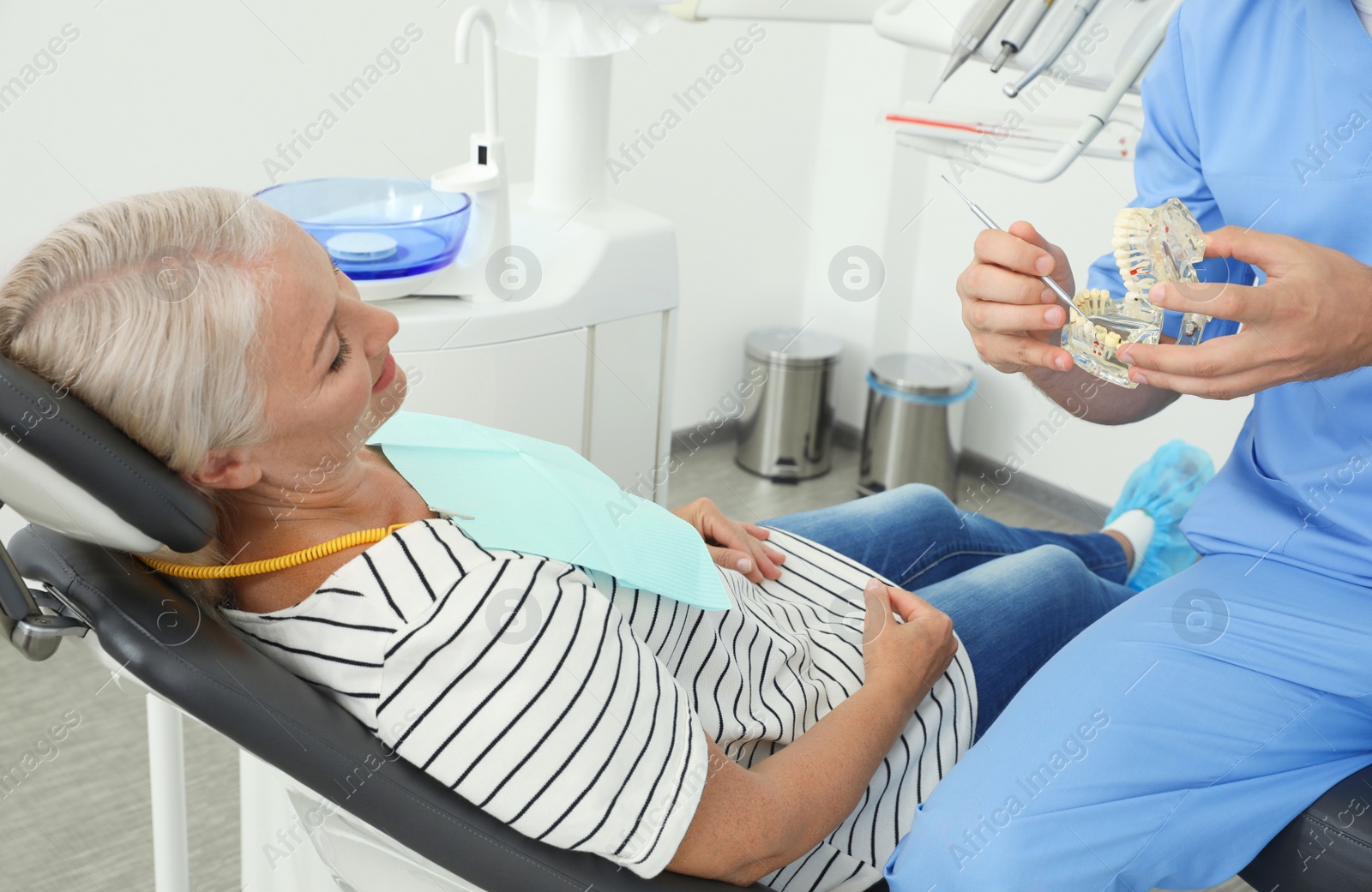 Photo of Professional dentist showing patient jaws model in clinic