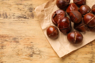 Photo of Fresh edible sweet chestnuts on wooden table, top view. Space for text