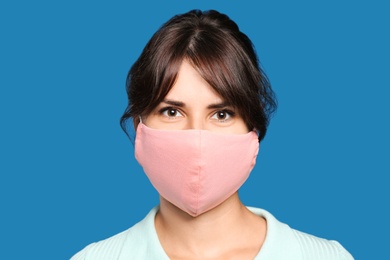 Photo of Young woman in protective face mask on blue background