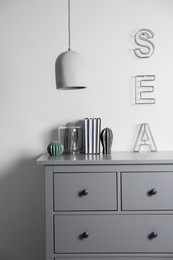Photo of Grey chest of drawers near light wall in room