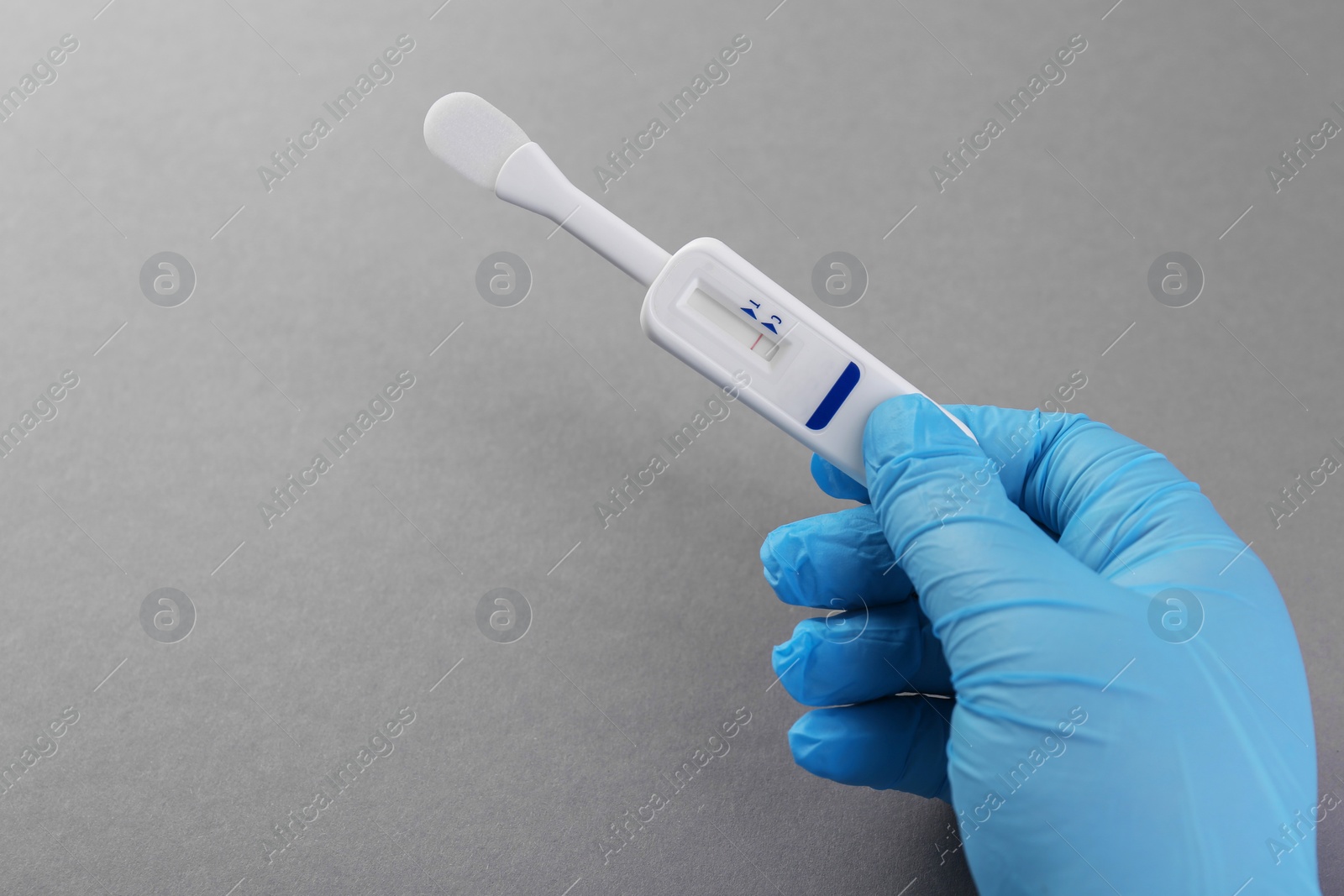 Photo of Doctor holding disposable express test on light grey background, closeup. Space for text