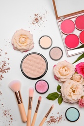 Photo of Flat lay composition with makeup brushes, cosmetic products and flowers on white background