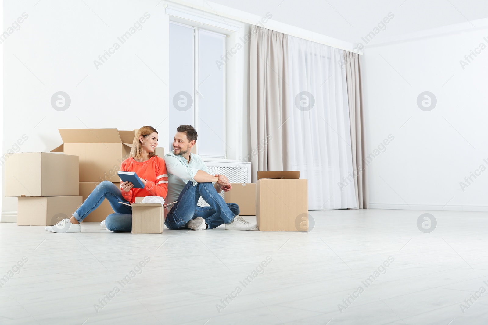 Photo of Couple unpacking moving boxes in their new house