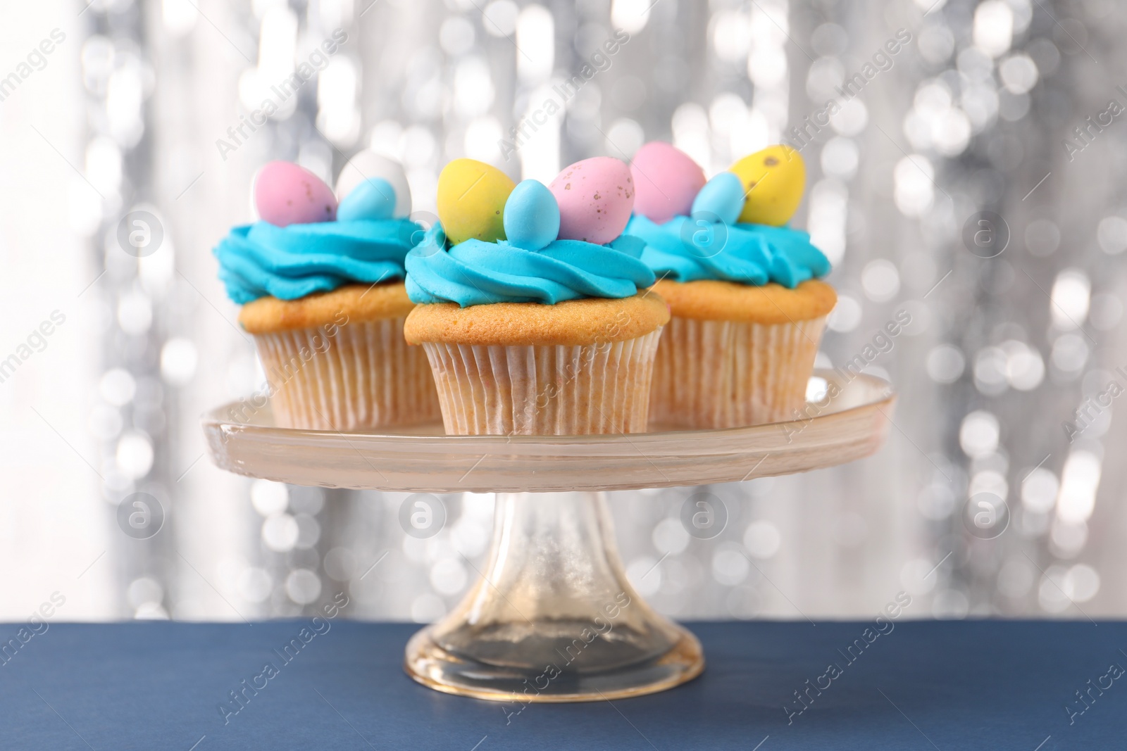 Photo of Tasty decorated Easter cupcakes on blue table, closeup