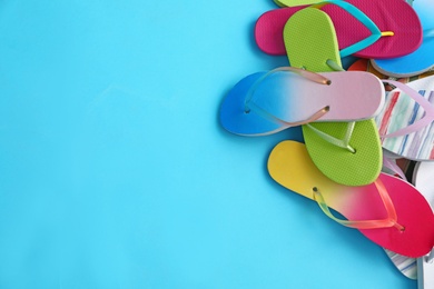 Photo of Heap of different flip flops and space for text on blue background, top view. Summer beach accessories