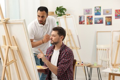 Photo of Artist teaching his student to paint in studio. Creative hobby