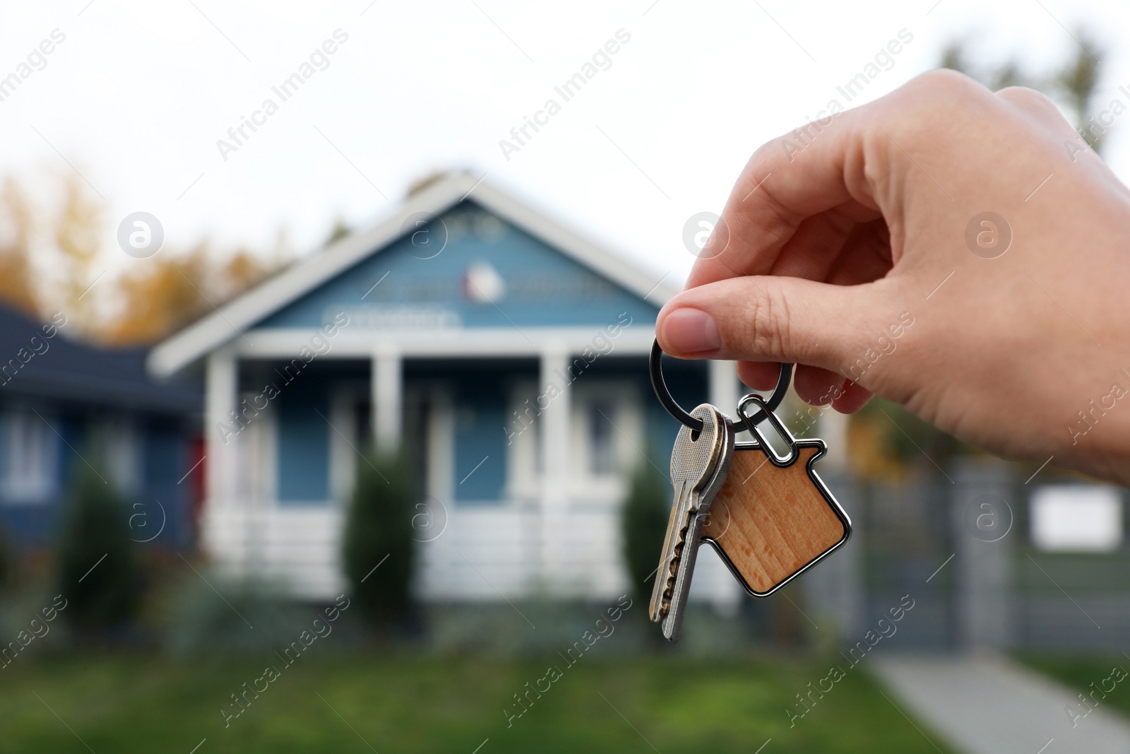 Photo of Woman holding house keys outdoors, closeup with space for text. Real estate agent