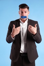 Man with taped mouth on light blue background. Speech censorship