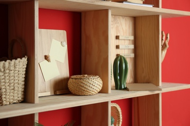 Photo of Stylish wooden shelf with decorative elements on red wall