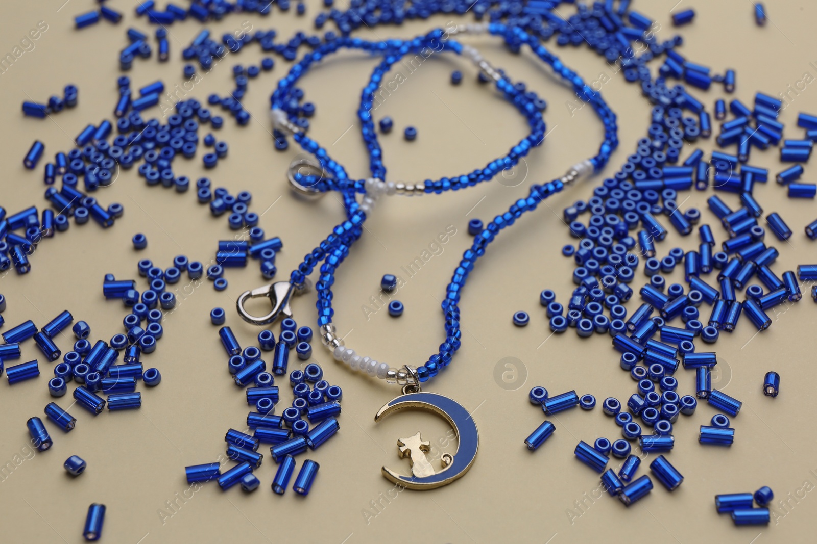 Photo of Bright blue glass beads and beautiful necklace on beige background
