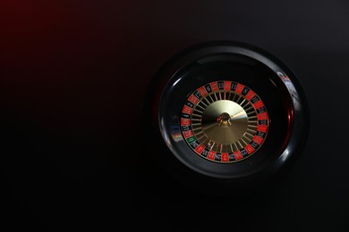 Photo of Roulette wheel with ball on black table, top view and space for text. Casino game