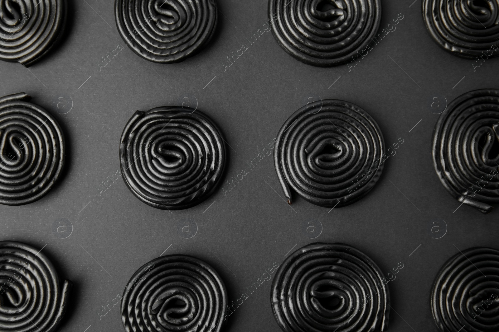 Photo of Tasty liquorice candies on black background, flat lay