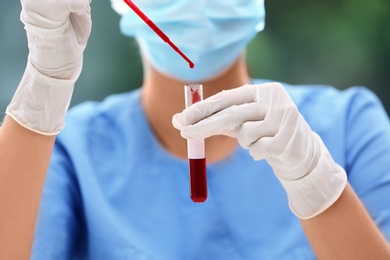 Scientist dripping blood into test tube in laboratory