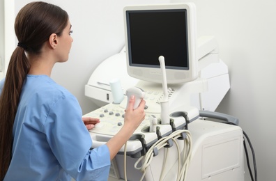 Sonographer operating modern ultrasound machine in clinic