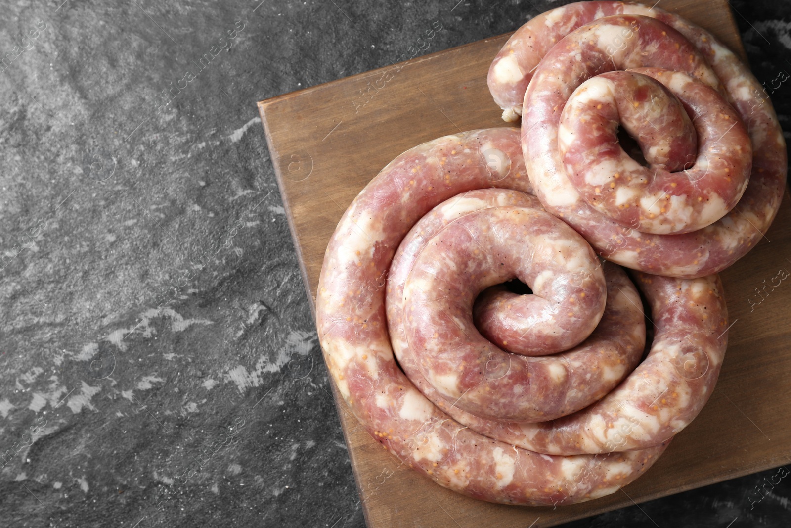 Photo of Raw homemade sausages on grey textured table, top view. Space for text