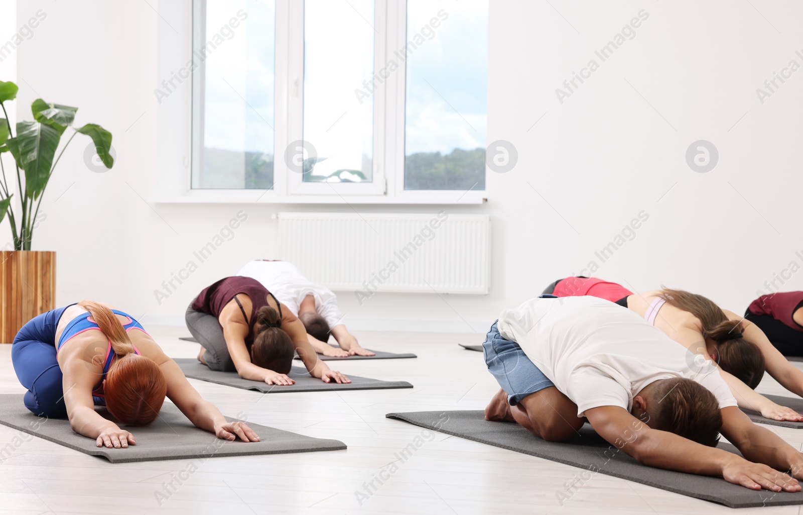 Photo of Group of people practicing yoga on mats indoors