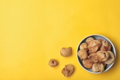 Bowl of dried figs on color background, top view with space for text. Healthy fruit