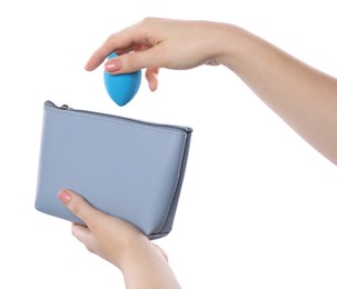 Photo of Woman putting makeup sponge into cosmetic bag on white background, closeup