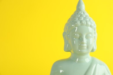 Photo of Beautiful ceramic Buddha sculpture on yellow background. Space for text
