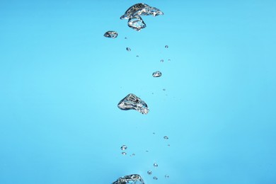 Photo of Air bubbles in water on light blue background