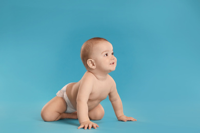 Photo of Cute little baby in diaper on light blue background
