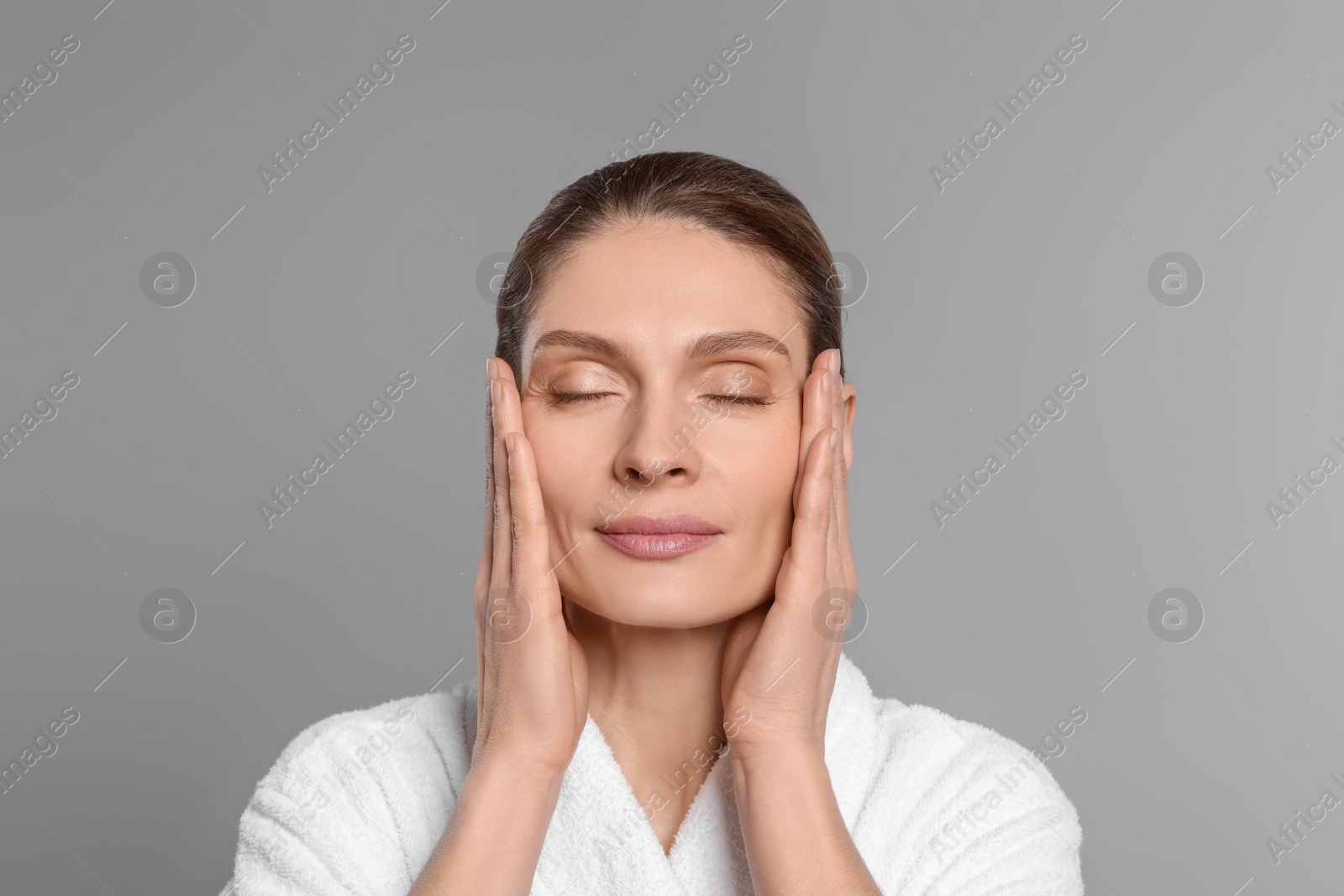 Photo of Woman massaging her face on grey background