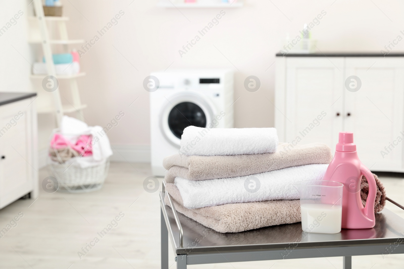 Photo of Soft bath towels and detergent on table against blurred background, space for text