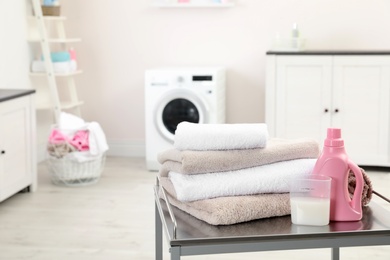 Soft bath towels and detergent on table against blurred background, space for text